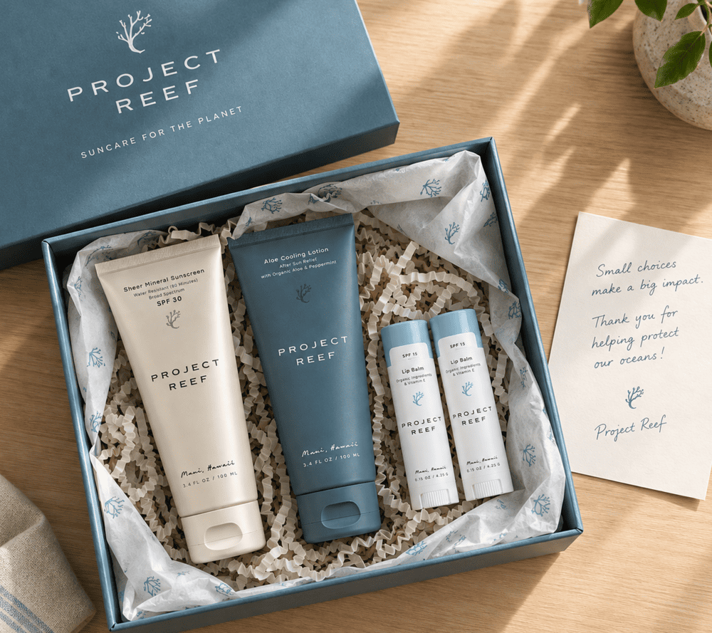 A beautifully curated client gift box by Project Reef sitting on a wooden desk next to a handwritten thank-you card.