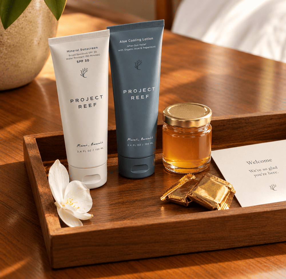 Hotel welcome amenity tray with Project Reef mineral sunscreen, local honey, and artisan chocolate.