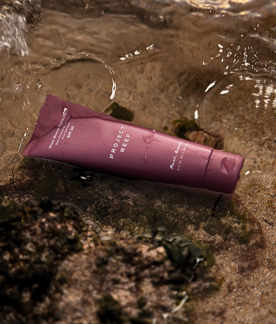 Project Reef SPF 50 sunscreen tube lying on a beach.